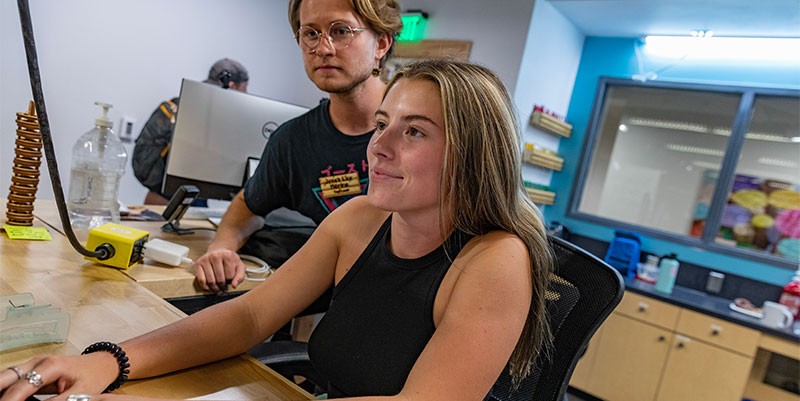 Two students work together on special equipment in the fabrication lab at the Innovation Hub