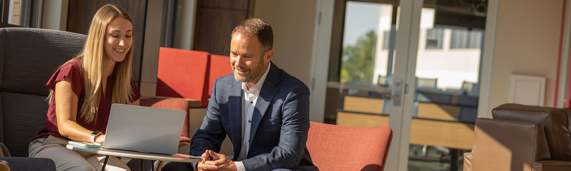Two people sit together looking at a laptop. 