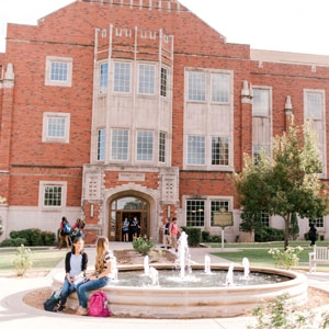 Exterior of Price Hall with students sitting at the fountain