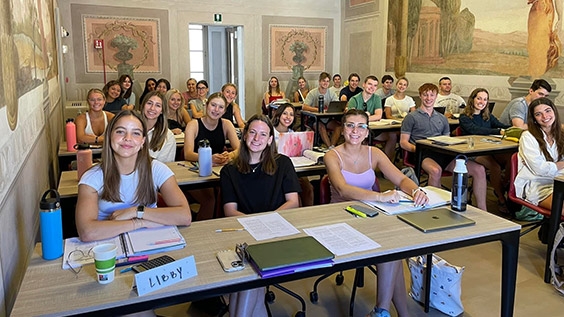 a group of students sitting at desks in a classroom in Arezzo, Italy.