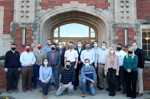 18 students in the Executive MBA in Energy program pose for a group photo outside of Adam's Hall at the OU Norman campus. 