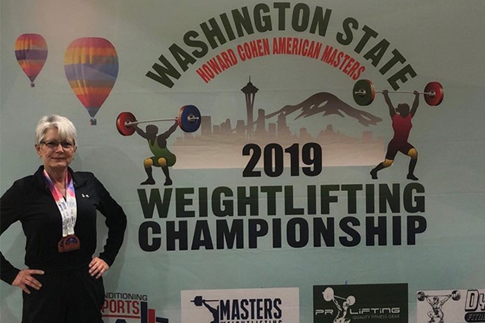 Jocelyn Pederson poses next to weight lifting competition sign