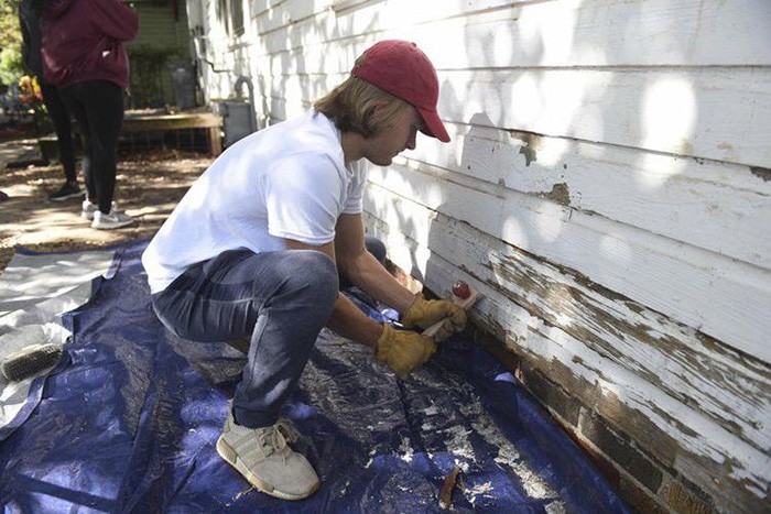 Student painting a house as part of Price College Service day