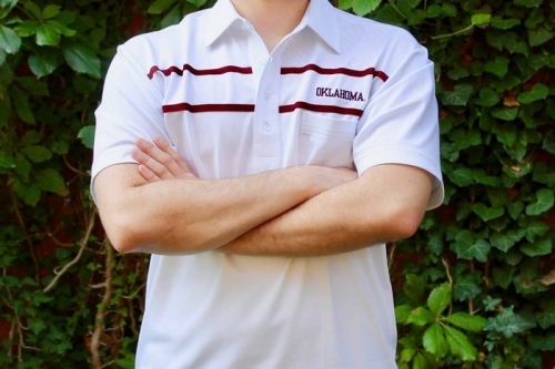 Man standing with arms crossed wearing an OU polo