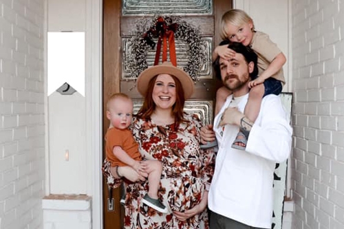 Nate Cross with wife and two children pose for a photo ourside of their home