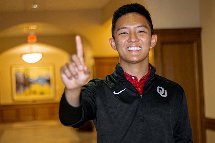 Price College student Phillip Suh holds up his right index finger in the middle of a hallway in Price Hall.
