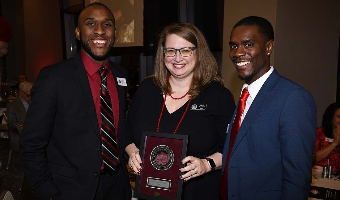 Marcia Plumbtree (center) is presented with membership plaque by two OU student at the annual Adams Society Gala