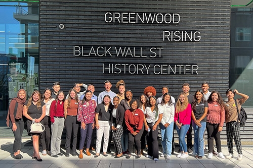 32 participants from the Price MBP program take a group photo in front of the Greenwood Rising Black Wall St. History Center in Tulsa, OK.