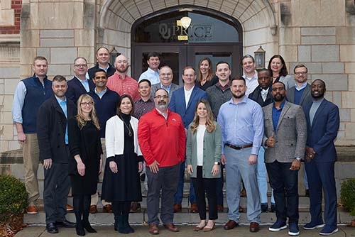 Group photo of EMBA Cohort 17 standing outside of the Adams Hall entrance on the Norman campus