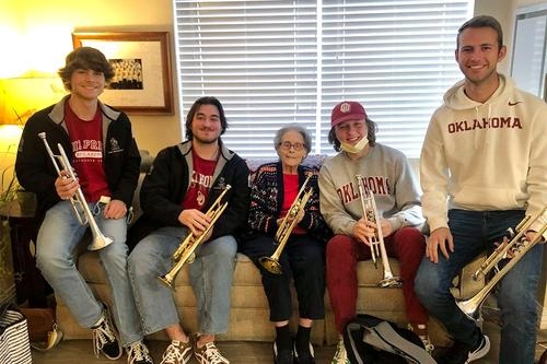 Four students from "The Pride of Oklahoma" sit together with their instruments visit a former OU trumpet player