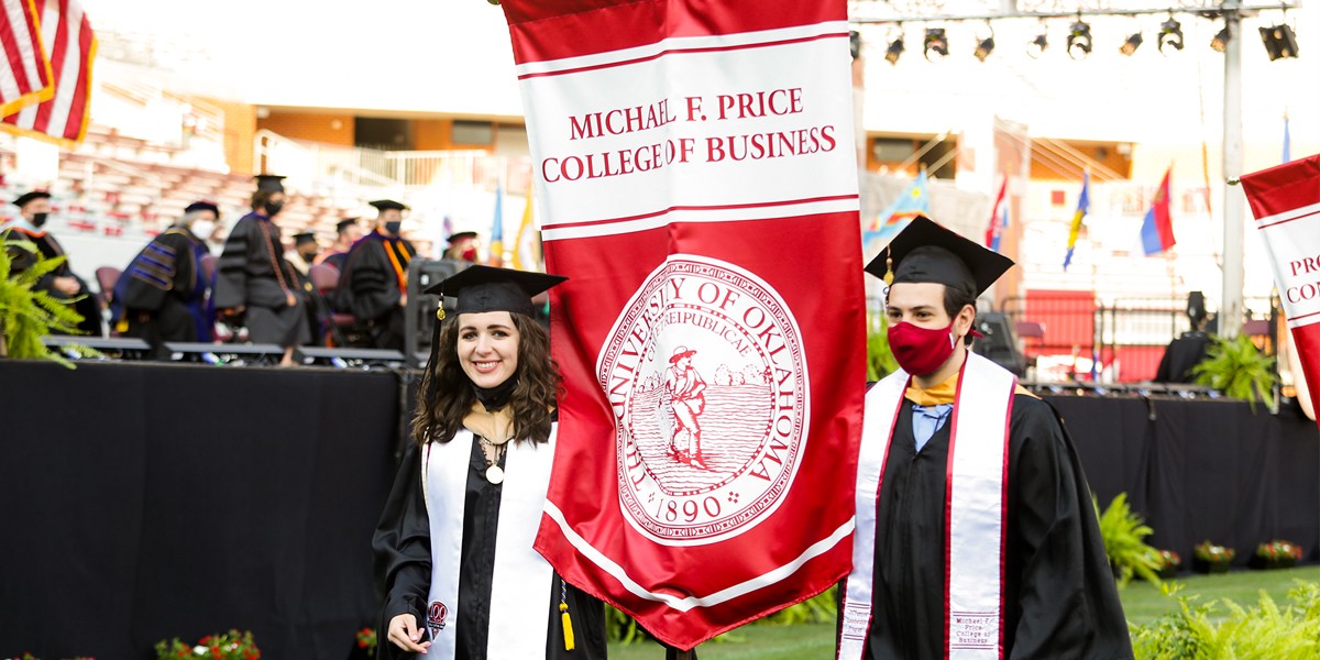 Two Price College students carry the Price banner at the 2021 commencement ceremony