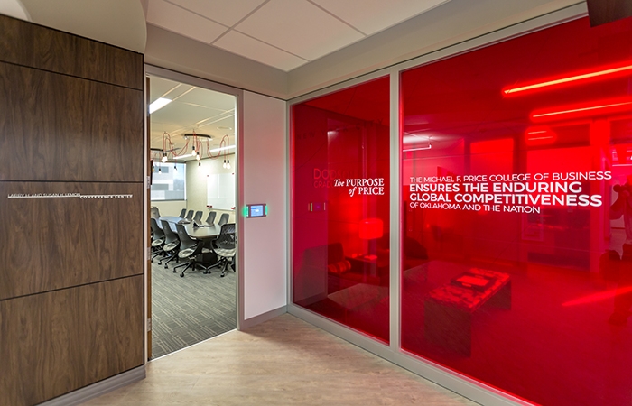 The slogan: The Purpose of Price, The Michael F. Price College of Business, Ensures the enduring global competitiveness of Oklahoma and the nation appears on a red-tinted glass wall in the Gene Rainbolt Graduate School of Business