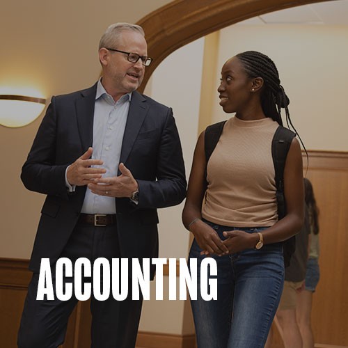 Dean Phelps and a student having a conversation as they walk through the halls of Price College. Text over the photo reads: Accounting.