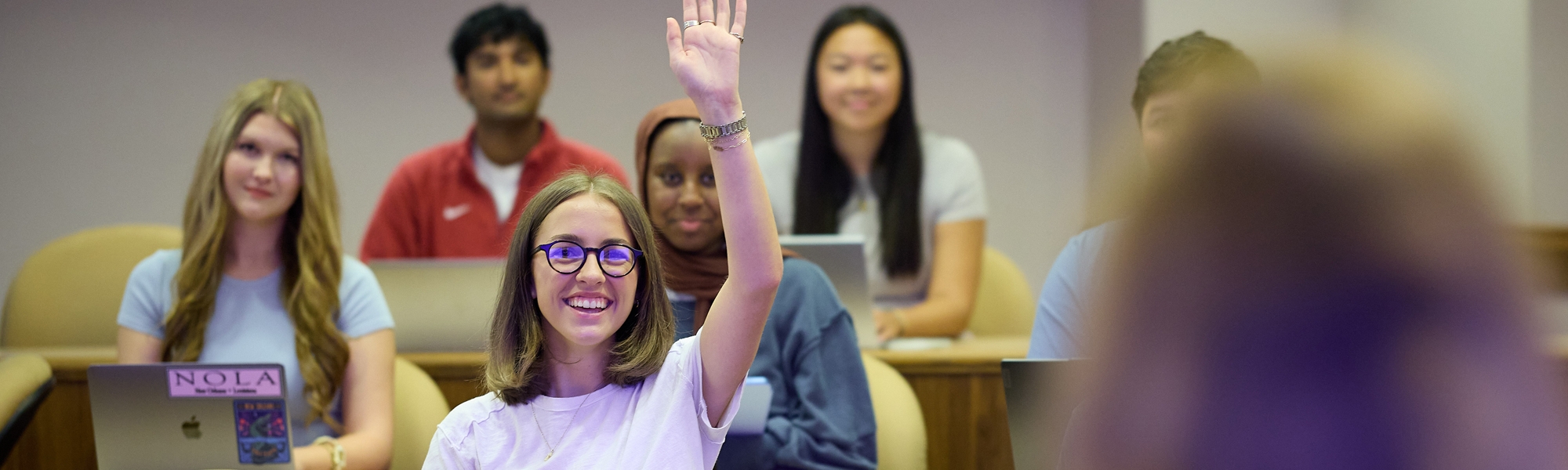 A student raising her hand during class. 