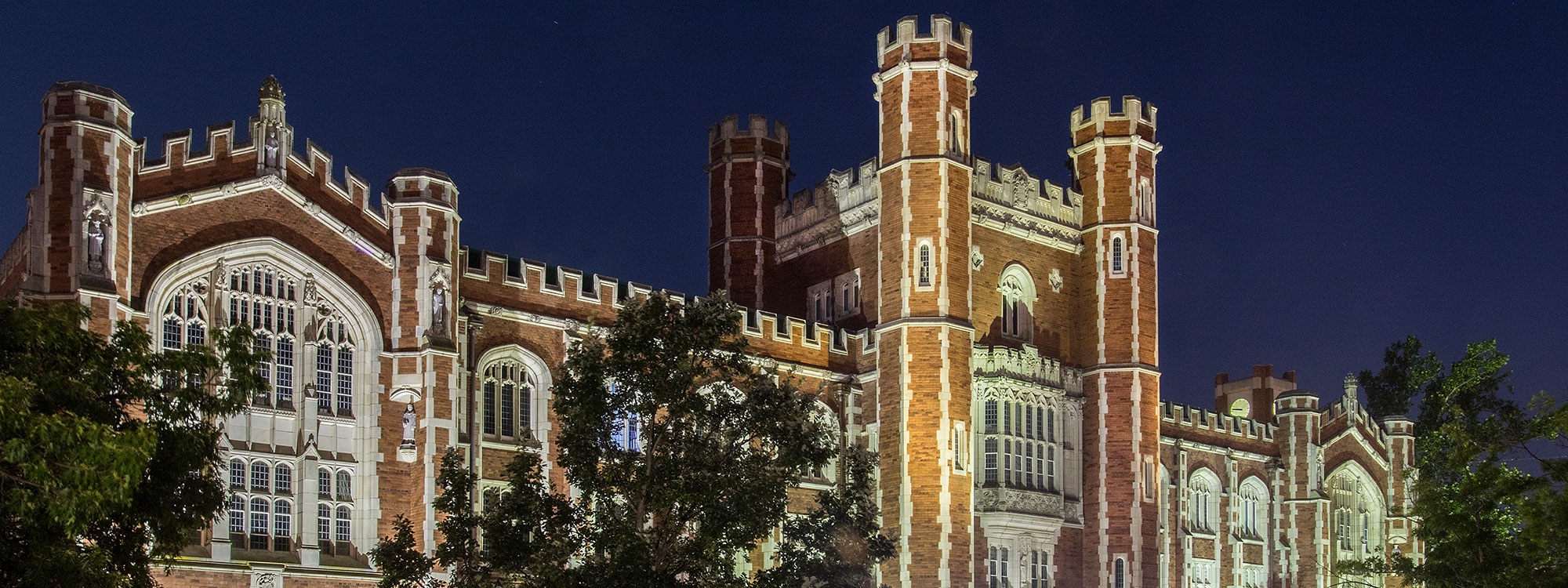 Bizzell Memorial Library at night, surrounded by trees.