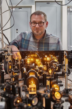 OU professor Arne Schwettmann works on a laser-cooling apparatus. 