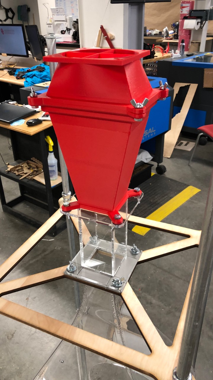 A custom designed aerosol measurement chamber to help measure aerosol production during certain vocal activities, like singing, speaking, laughing, or sneezing. A fan is inside the red assembly, pulling air through the full system.