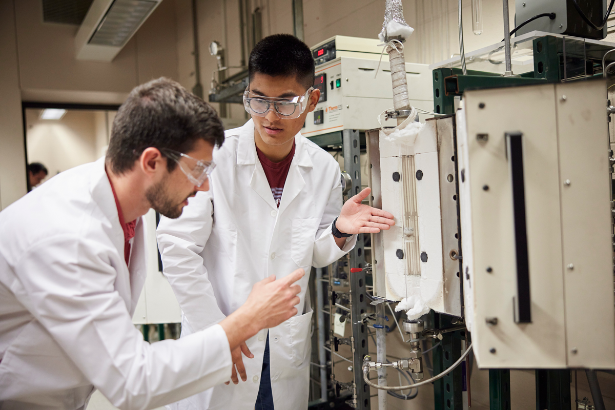 Graduate students Nilson F. L. de Paula and Ethan Zhang discuss operation of fluidized bed reactor.