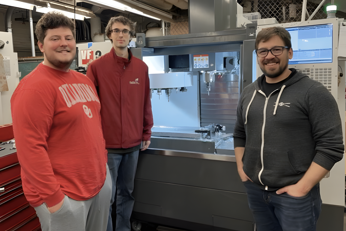 OU students, Tristen Portis (left), John Pickrell and Rick Lucio (right), pose in front of a CNC machine