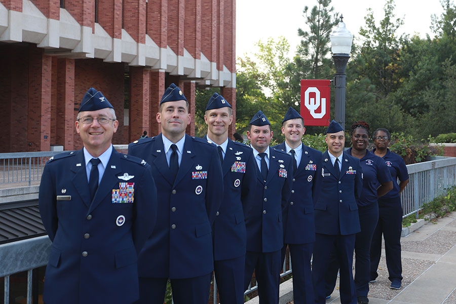 Staff members of Det 675 Cadre for the 2023 to 2024 Academic Year standing in a row in front of a lamppost with OU flag.