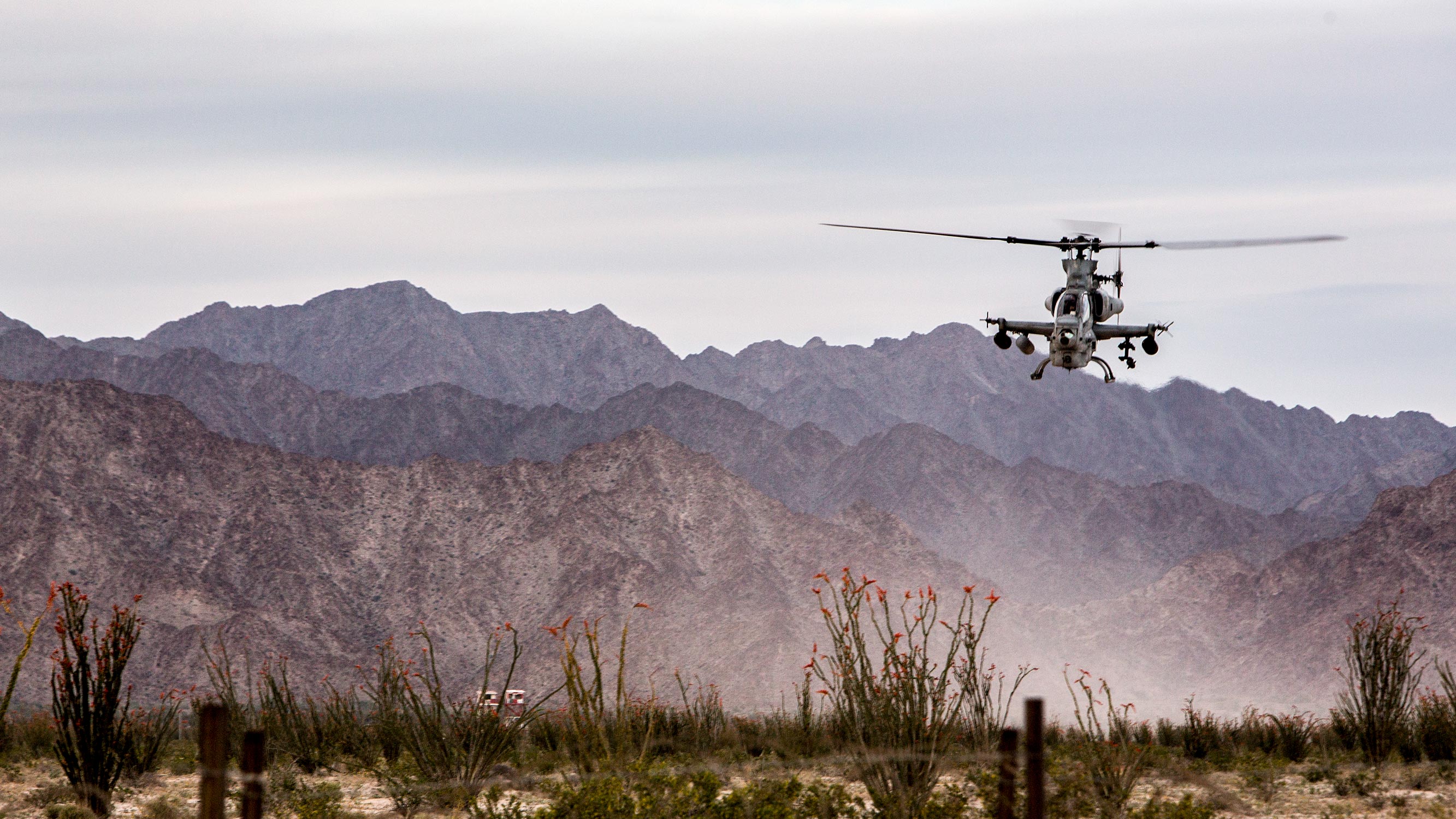 Helicopter hovering low to the ground in the desert.