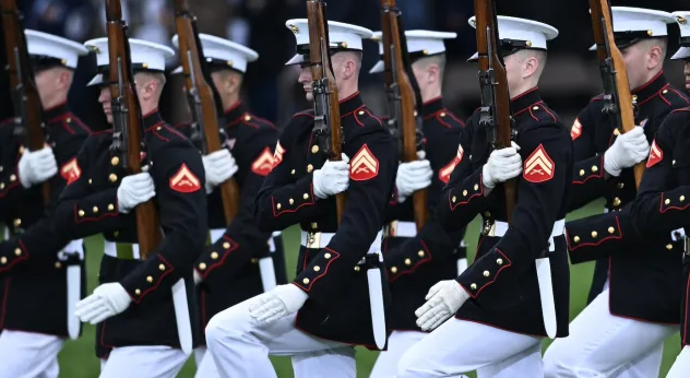 NROTC guard kneeling in formation with their rifles.