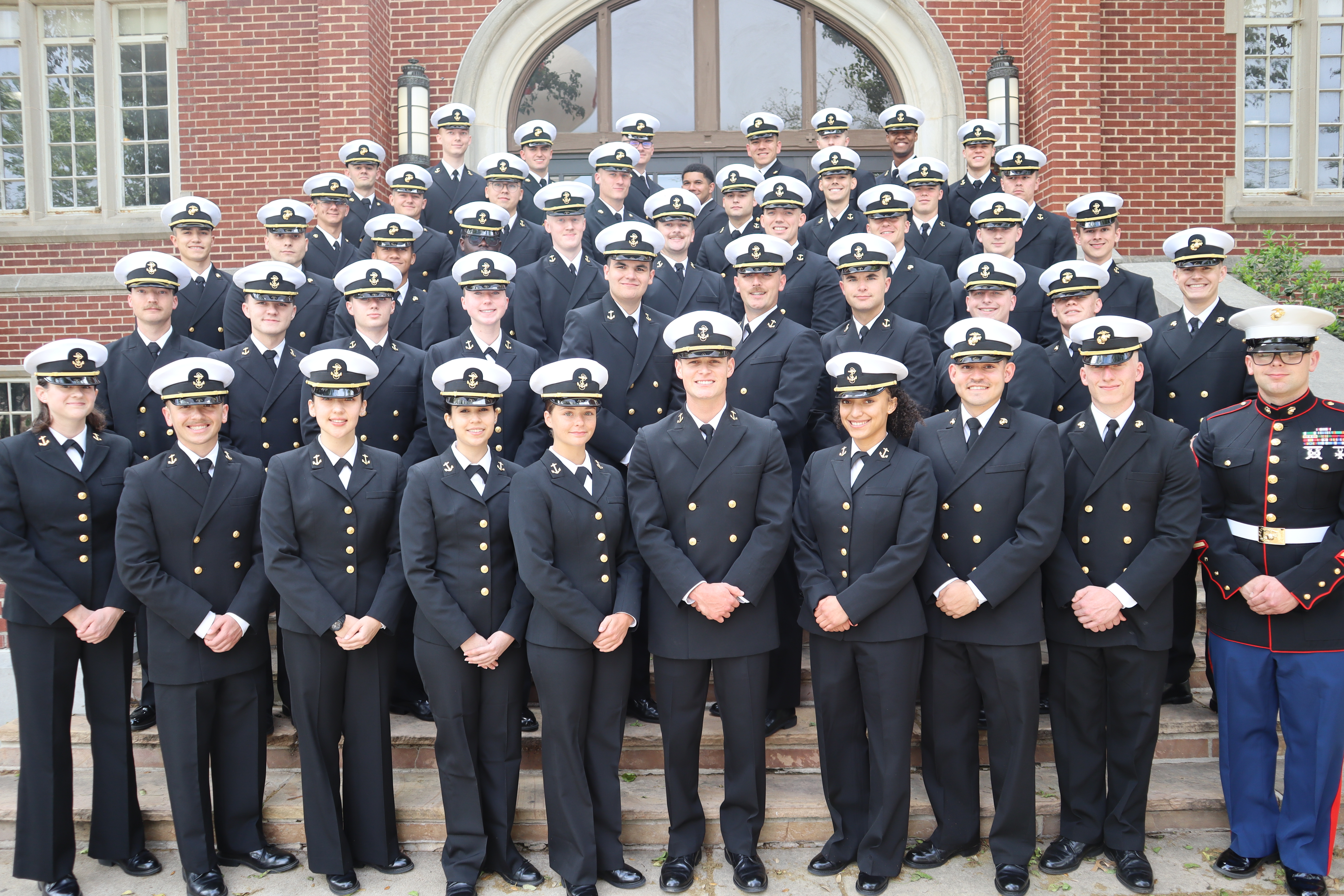 NROTC class posing in front of Adams Hall in their uniforms.