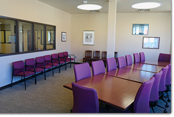 conference room with large table and chairs around it, chairs along wall