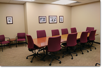 room with long conference tables surrounded by chairs; chairs along the walls