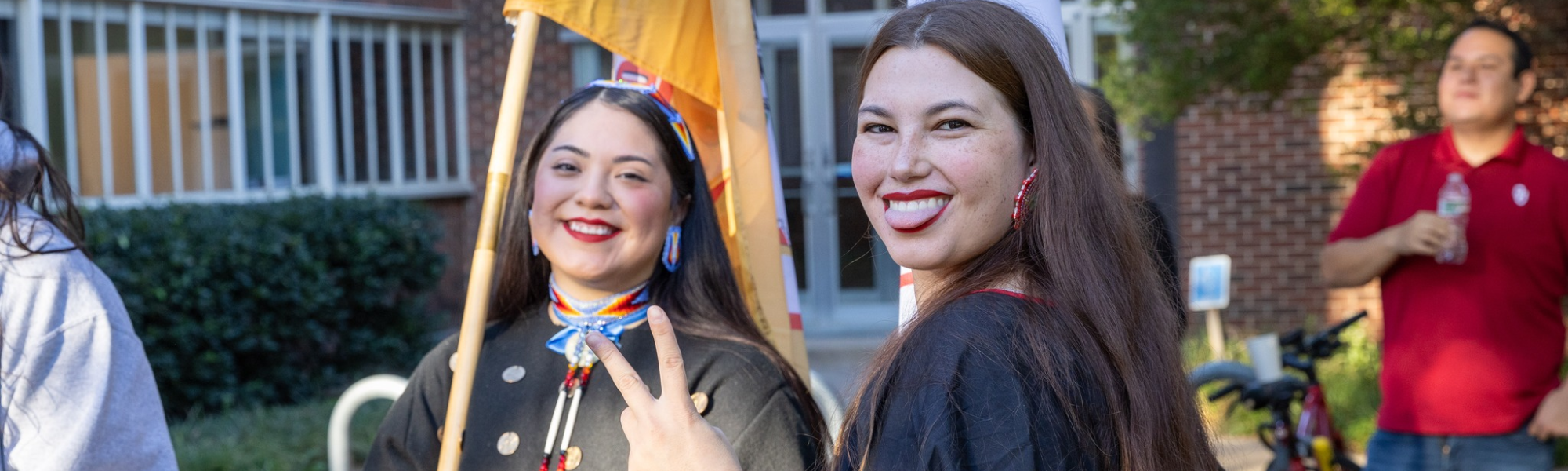 Two students in traditional Native American clothing smiling.