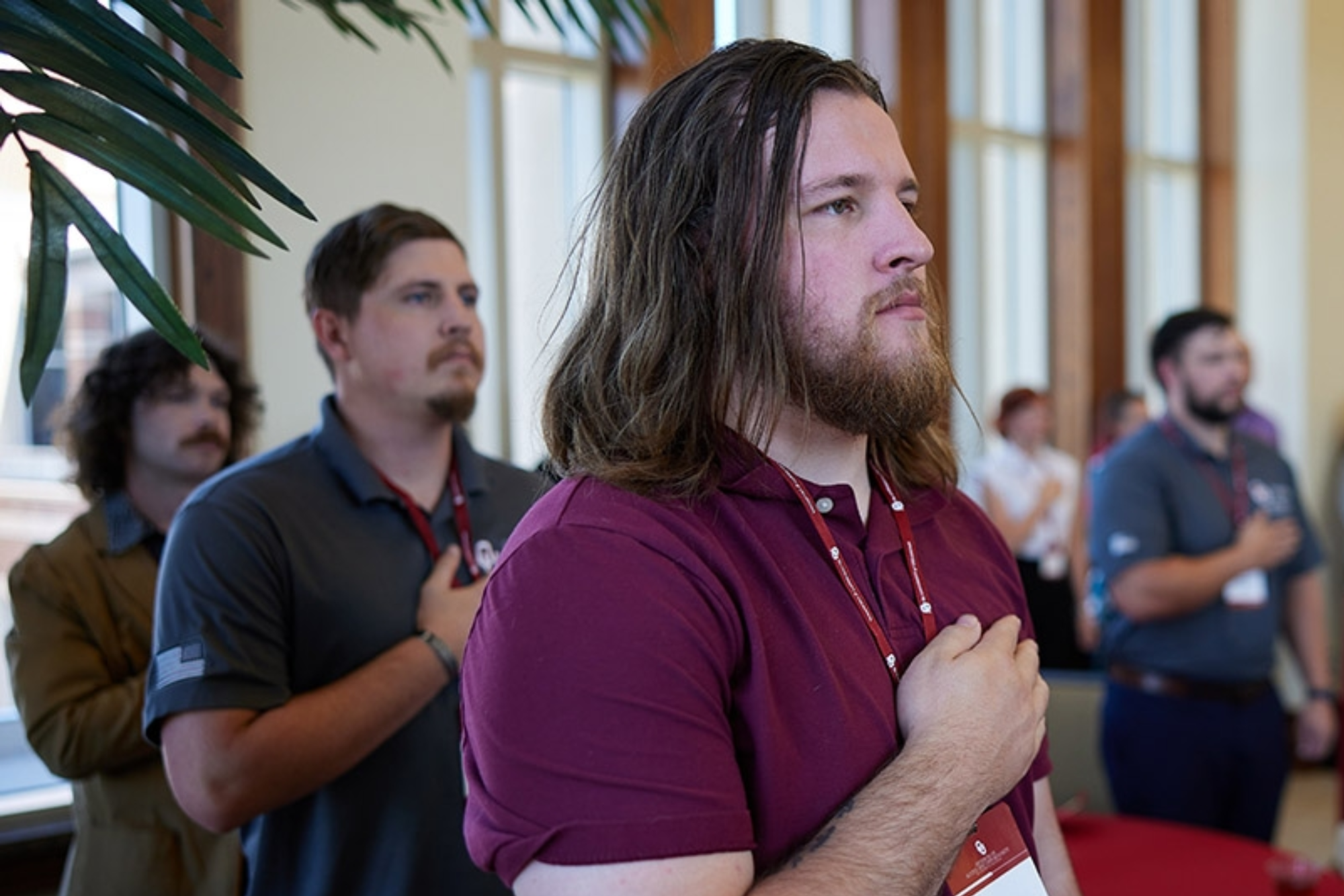 Attendees of the 2024 MVC Reception salute the flag during the National Anthem before the event.