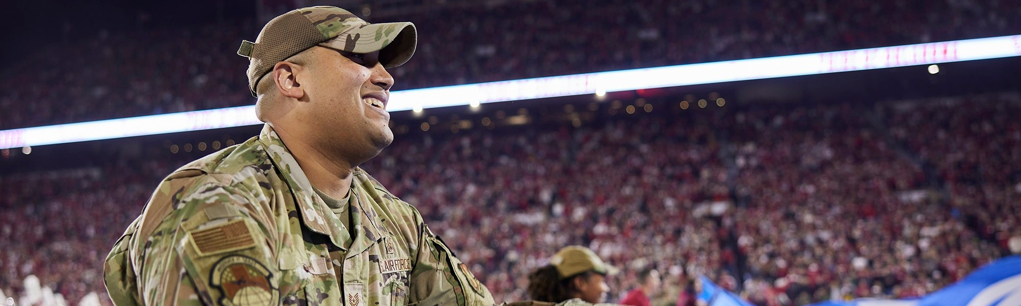 Military member in uniform holding part of the Oklahoma state flag before OU vs West Virginia game on November 11, 2023.