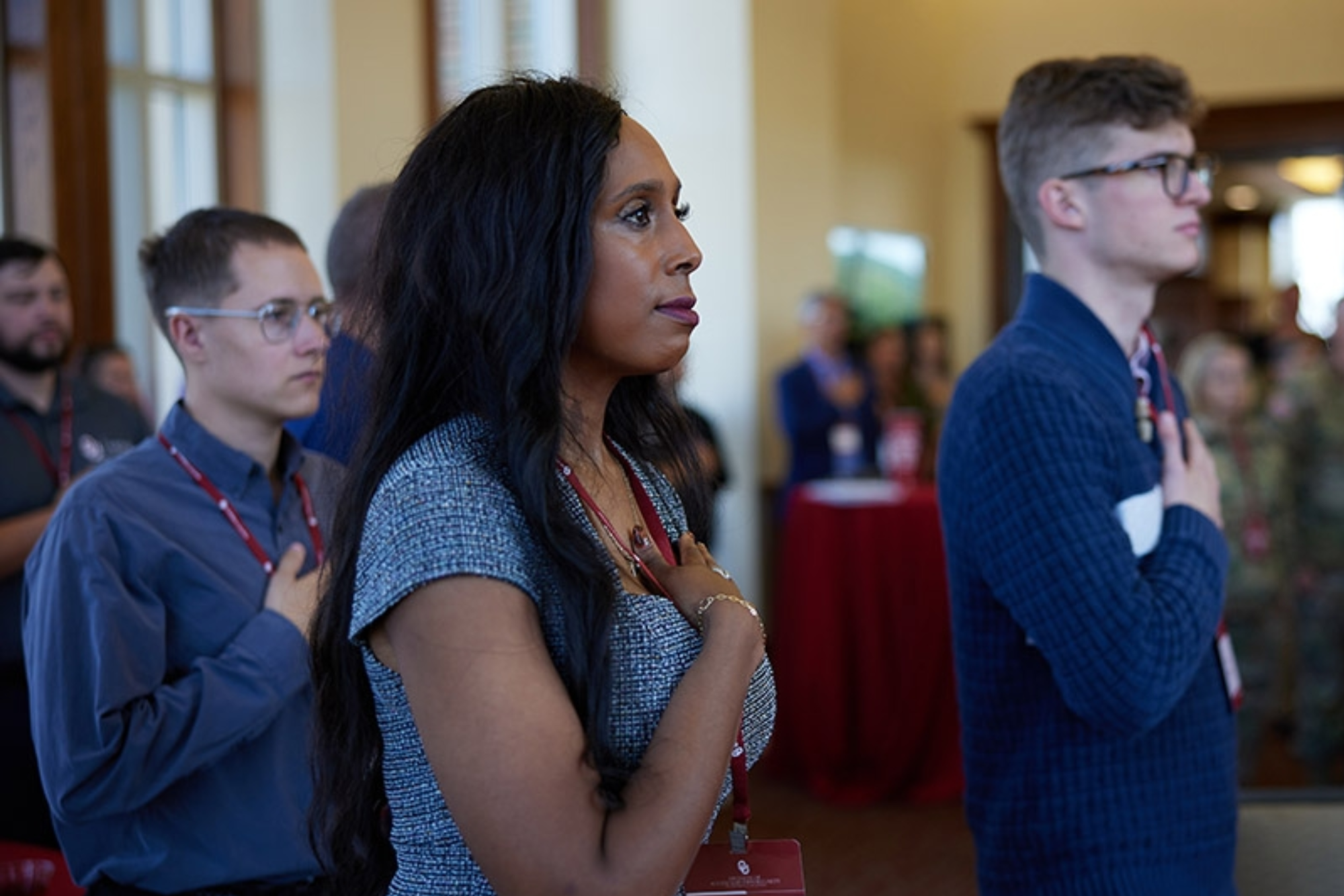 Attendees of the 2024 MVC Reception salute the flag during the National Anthem before the event.