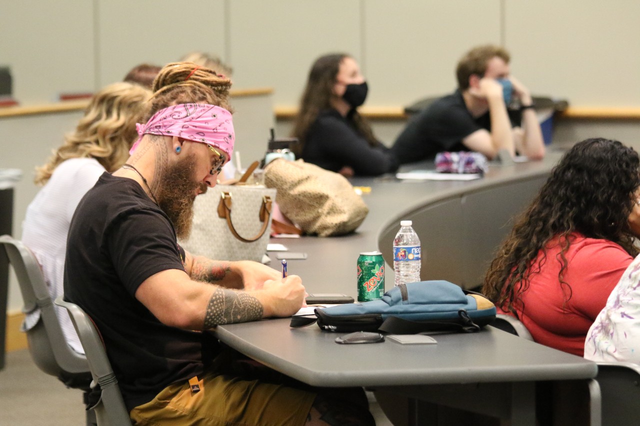 Student taking notes during course lecture