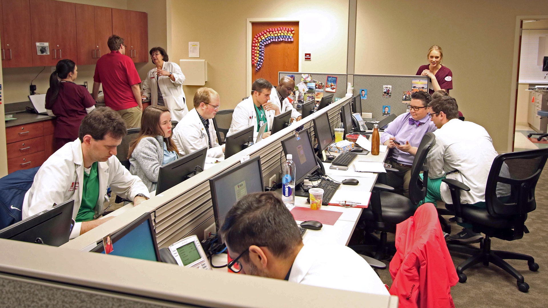 Several doctors and nurses gather in the bullpen at the OUSCM Bedlam Clinic