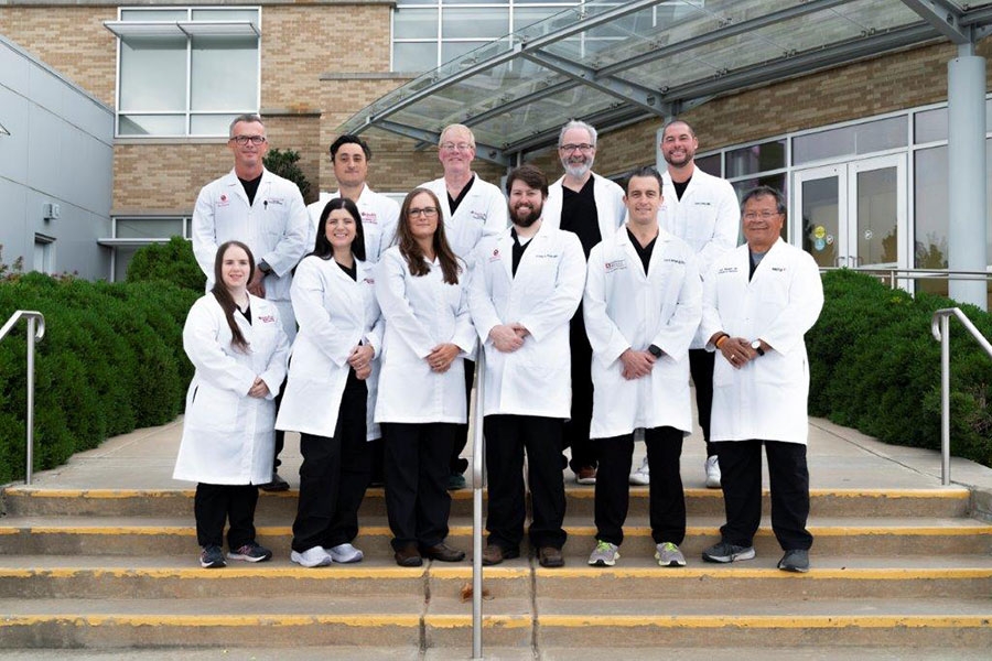 The faculty of the Emergency Medicine Department posing for a group photo on a set of stairs.