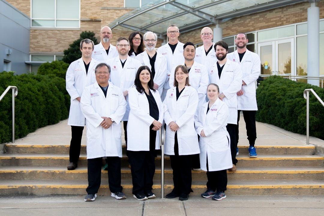 The faculty of the Emergency Medicine Department posing for a group photo on a set of stairs.