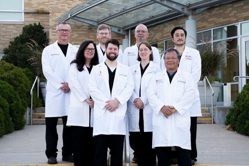 The faculty of the Emergency Medicine Department posing for a group photo on a set of stairs.