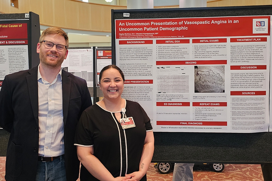 A pair of OU Tulsa medical students in front of their presented research board.