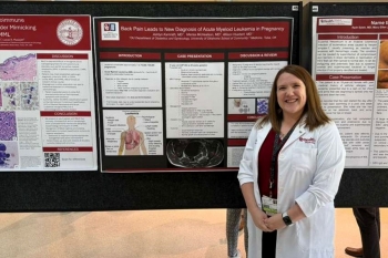 An OBGYN faculty member standing in front of posters.