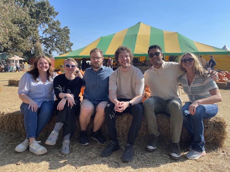Six residents sitting on a long haybale together.