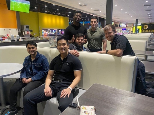 Students sitting around a bowling lane sitting area.