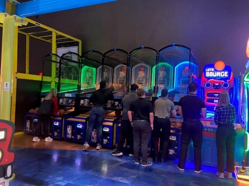 Students at an arcade throwing basketballs.