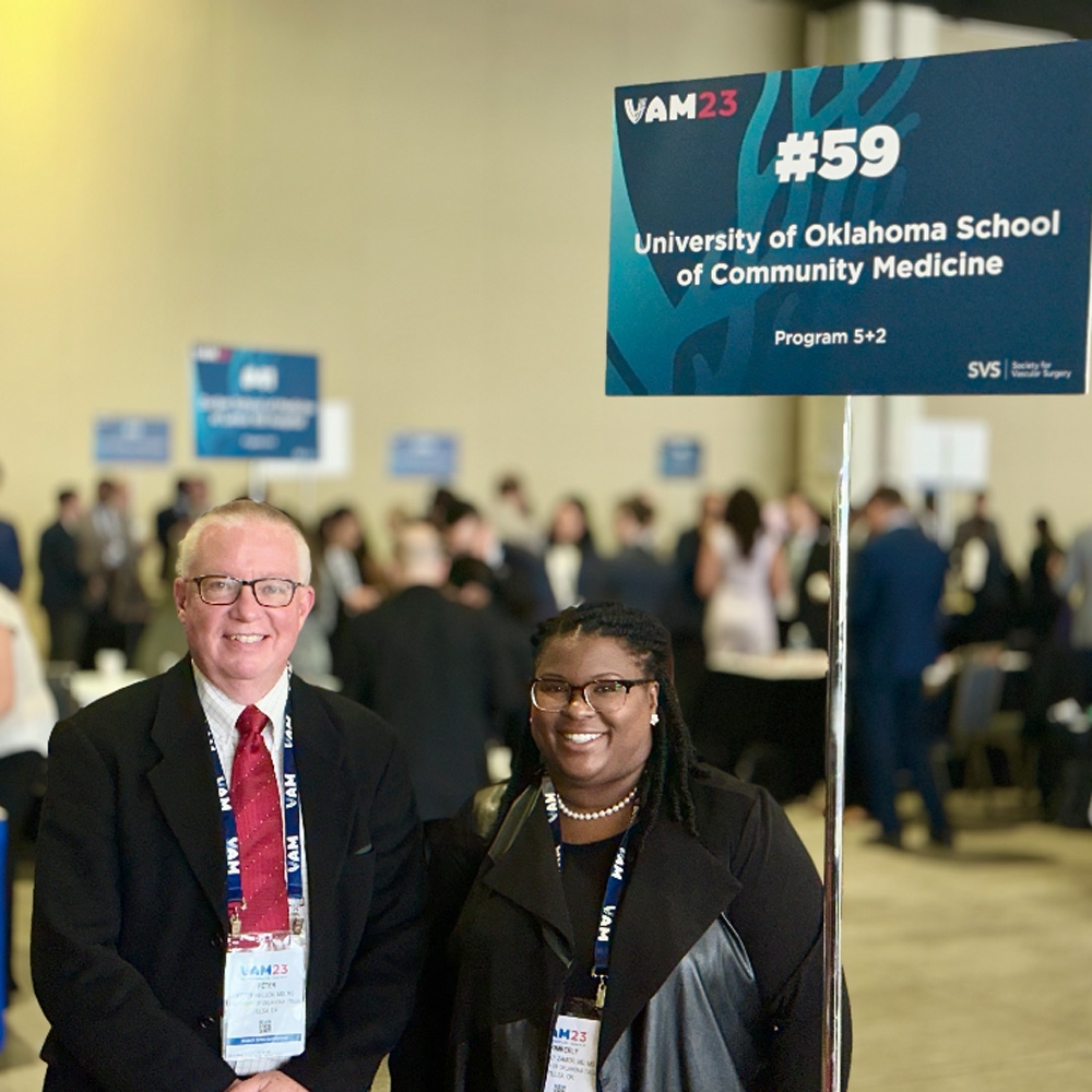 Two people at a school of medicine conference sign.