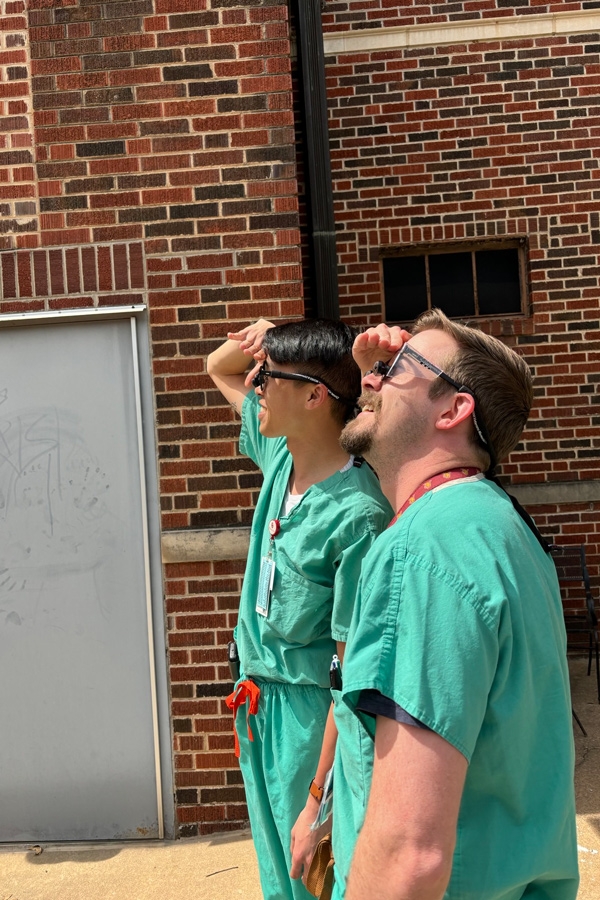 Wellness residents in scrubs looking at the sky outside.