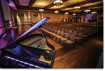 ballroom with grand piano and rows of chairs