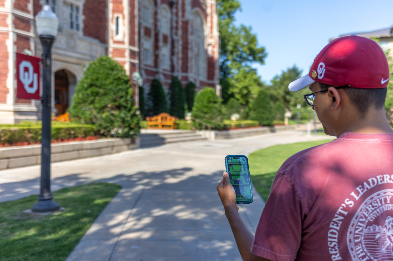 A student looking at a cell phone outside.