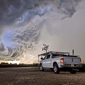 TORUS storm observation vehicle in the foreground, with a storm in the background.