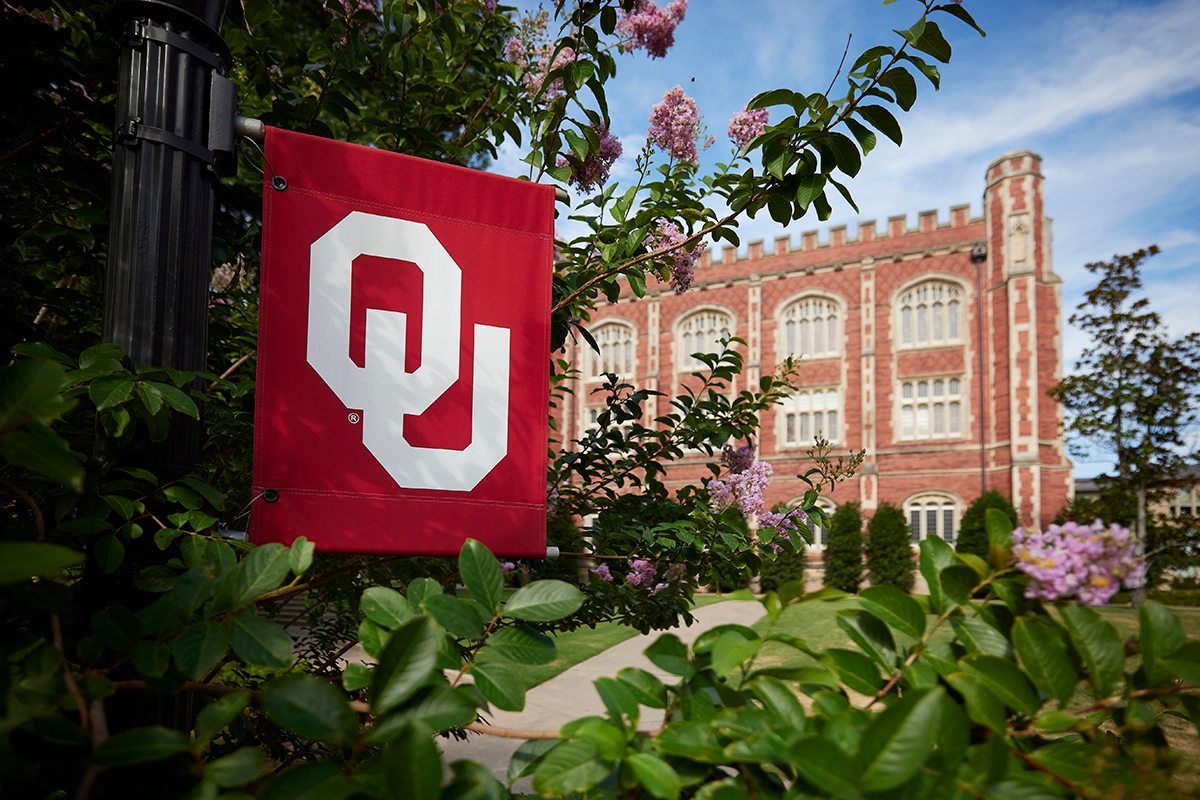 OU flag on University of Oklahoma campus in front of campus building